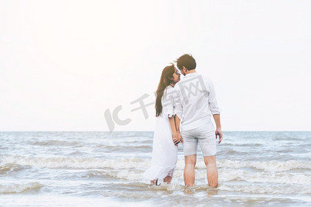 在蜜月旅行假期期间走在海滩上的愉快的年轻夫妇。情侣去热带海滩蜜月在夏天
