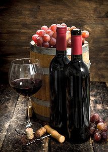 木桶摄影照片_葡萄酒背景。一桶红酒和新鲜葡萄。在木制的背景上..葡萄酒背景。一桶红酒和新鲜葡萄。