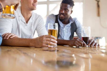 休闲和饮品概念-男性朋友在酒吧或酒吧喝啤酒。在酒吧或酒吧喝啤酒的男性朋友