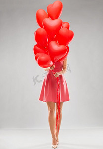 情人节，爱情和人的概念--年轻女子手持一串红色心形气球。戴着红心形气球的年轻女子