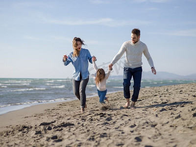 秋日，一家人带着小女儿在海滩上休息和玩耍。年轻幸福的家庭在秋日里享受着矢量