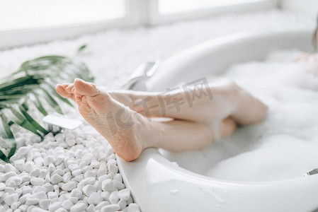 女性高跟鞋从浴缸里伸出，泡沫。浴室、水疗中心提供放松、健康和身体护理