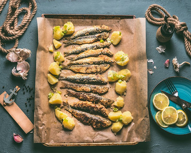 烤沙丁鱼配土豆在烤盘上，配料：柠檬，大蒜和香草美味的海鲜吃。鱼的烹饪制备