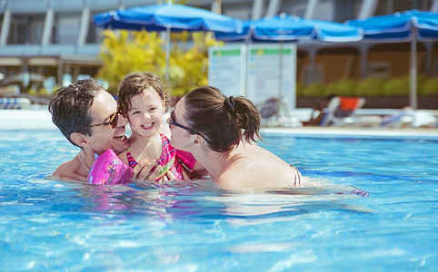 愉快的家庭在热带游泳池放松