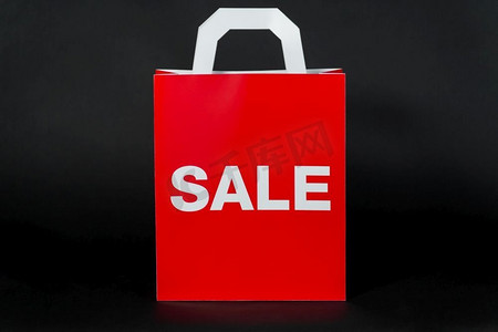 销售，消费主义和出口概念手拿红色购物袋在黑色背景红色购物袋与销售字样