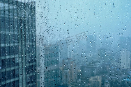 与水背景摄影照片_雨水滴在窗口玻璃纹理与摩天大楼在背景。雨点落在窗户上