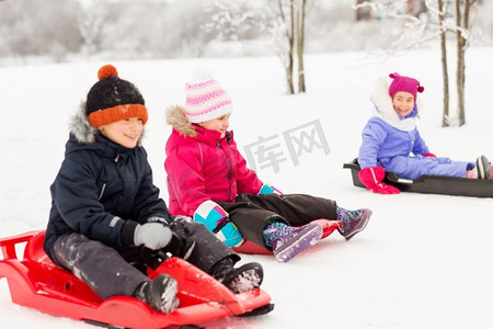 童年、雪橇和季节概念-一群快乐的小孩子在冬天滑雪橇。快乐的小孩子们在冬天滑雪橇