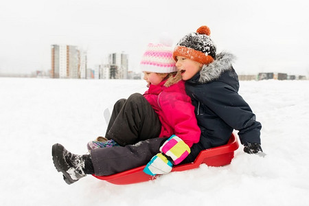童年，雪橇和季节概念—快乐的小孩子在冬天滑下雪山的雪橇。小孩子滑雪橇下山在冬天
