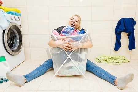堆洗衣服摄影照片_快乐有趣的女人在浴室与大篮子脏衣服。洗衣概念。家务活..女人与大篮子脏衣服洗衣。