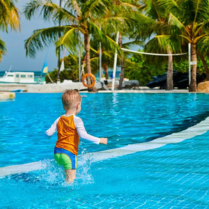 三岁的蹒跚学步的男孩在度假村游泳池。暑假在马尔代夫度假。