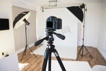 创意时尚摄影照片_摄影棚三脚架上的专业单反数码相机
