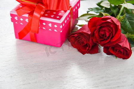 情人节礼品盒鲜花爱情概念/粉色礼盒白色木质背景上有彩带蝴蝶结红玫瑰花复制空间