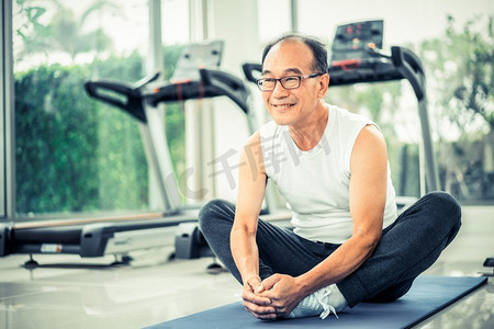 老年人锻炼摄影照片_老年人在健身中心做身体伸展运动。健康的生活方式。