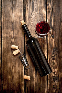 一瓶带开瓶器和软木塞的红葡萄酒。在一张木桌上..一瓶带开瓶器和软木塞的红葡萄酒。