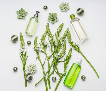 绿色草本植物自然化妆品设置与瓶子和花在白色背景，顶视图，平铺设美容护肤概念