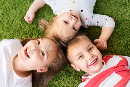 童年，休闲和家庭概念—快乐的小孩子躺在地板或地毯上。快乐的小孩子躺在地板或地毯上