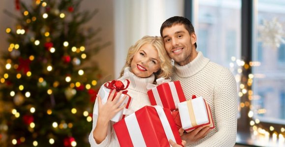 节日和人们的概念幸福夫妇在家中的圣诞树彩灯背景礼物。家里有圣诞礼物的幸福夫妻