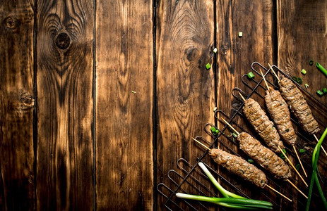 土耳其烤肉摄影照片_烤肉串和大葱。在一张木桌上。烤肉串和大葱。