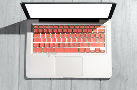 在阳光明媚的日子里，木桌上有活生生的珊瑚色键盘的笔记本电脑，从高处俯瞰。木桌上的笔记本电脑