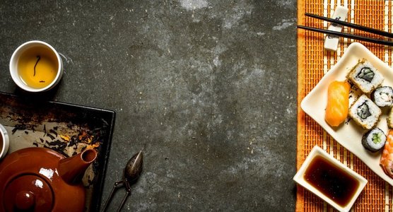 山葵摄影照片_日本料理。面包卷，寿司和热茶。在石桌上。日本料理。面包卷，寿司和热茶。