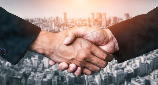 商业人士在城市办公大楼握手的双曝光图像背景显示商业交易的合作成功