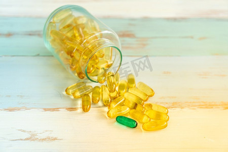 一个绿色药丸药站出来从黄色药丸和溢出的药丸瓶在葡萄酒木背景