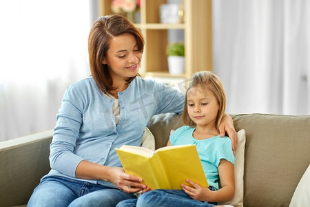 母亲读书摄影照片_人，家庭和教育理念—快乐的女儿与母亲读书在家。快乐的女孩与母亲读书在家里