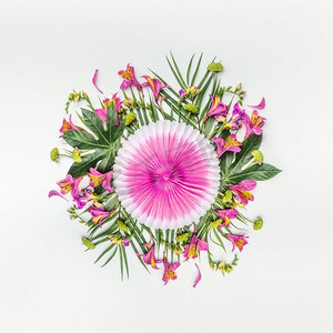 圆形树叶摄影照片_夏季热带圆形花卉组合，棕榈叶和粉色纸派对扇在白色背景上