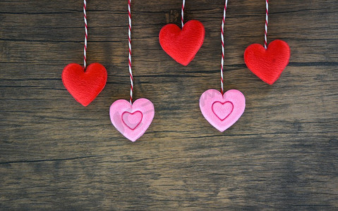 爱心粉红色摄影照片_情人节爱心概念/悬挂红色和粉红色心装饰在木质朴纹理背景 