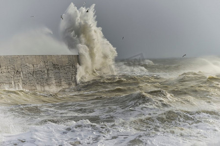 在英国海岸纽哈文的狂风风暴中，令人惊叹的海浪冲击着港口的墙壁。