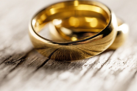 两个金结婚戒指在木背景宏观。两枚结婚戒指