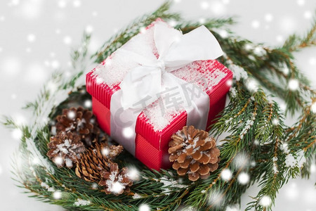 圣诞节，冬季假期和问候概念—礼品盒和冷杉花环与圆锥在雪。圣诞礼物和冷杉花环与圆锥在雪