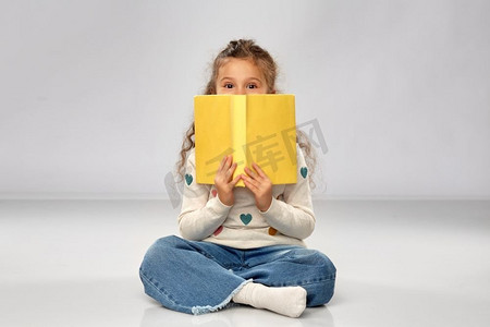 学习的小女孩摄影照片_阅读、教育和童年概念—坐在地板上的小女孩有书在灰色背景。小女孩与书坐在地板上