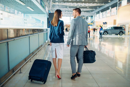 商务舱乘客带着行李在机场，后视。航站楼里的商人和女商人，谈判之旅