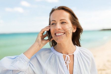 人和休闲概念—愉快的微笑的妇女呼叫智能手机在夏天海滩快乐的女人呼叫智能手机上夏季海滩