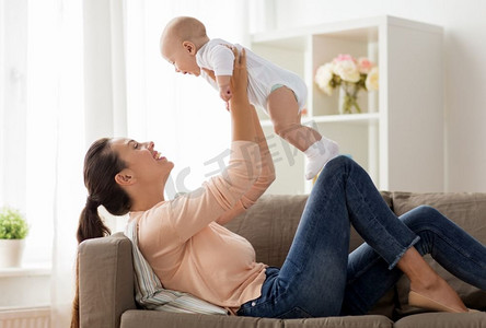 家庭，母性和人的概念—快乐的母亲在家里玩小男婴。快乐的母亲玩与小男婴在家里
