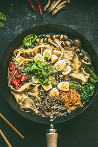 俯视俯视锅摄影照片_炒锅与素食韩国火锅和筷子的特写，在深色乡村厨房桌子的背景下，俯视。复制空间。亚洲食品概念
