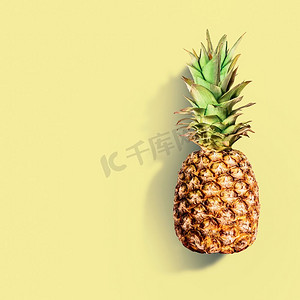 夏季水果创意摄影照片_黄底的菠萝。夏季热带水果概念。为您的设计复制空间