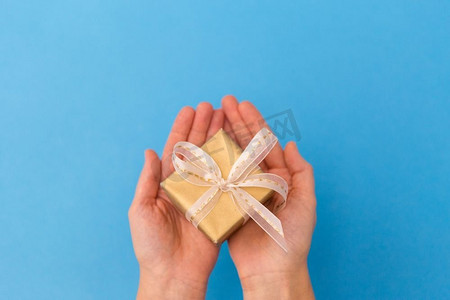 节日，礼物和问候概念—手拿着小圣诞礼物盒在蓝色背景手拿小圣诞礼盒