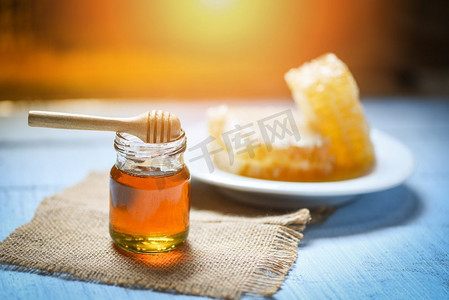 蜂蜜在罐子里有木勺和蜂窝在白色板的自然健康食品在桌子背景  