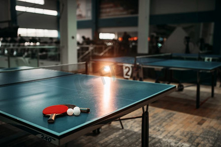 体育馆里的乒乓球桌上有球拍和球，还有比赛设备。室内网球俱乐部