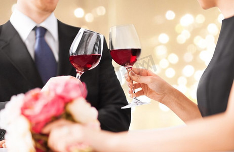 庆祝，饮料和酒精概念-情侣的手碰杯红酒杯。情侣手碰红酒杯