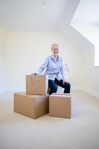 老年妇女的肖像削减退休坐在箱子在新家在搬家日