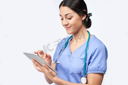工作室拍摄的女护士穿着磨砂膏使用数字平板电脑   