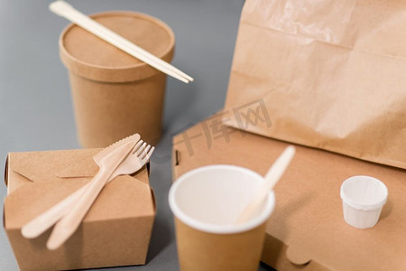 印刷包装设计摄影照片_包装、回收和食用概念--餐桌上的一次性纸质外卖食品容器。用于外卖食品的一次性纸质容器