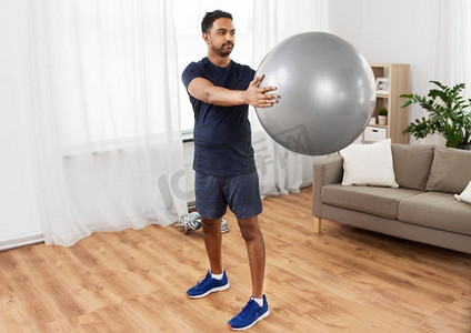 健身，运动和健康的生活方式概念—印度男子在家里用球锻炼。印度男子在家里锻炼健身球