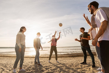 打排球的摄影照片_排球，休闲游戏和人的概念—快乐的朋友在沙滩上玩球在夏天。夏天在沙滩上打排球的朋友