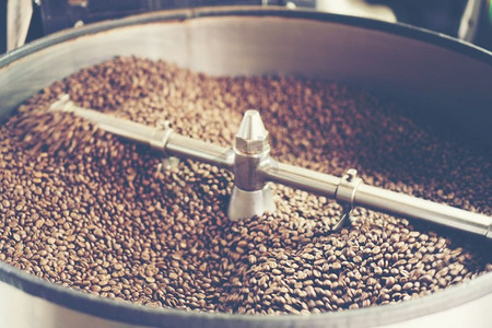 新鲜烘焙芳香咖啡豆在现代咖啡烘焙机，老式过滤器图像