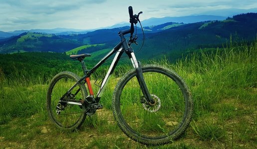 骑车的好处摄影照片_一辆自行车从后面的山丘上飞过。骑车探险和旅行的象征。健康生活方式理念