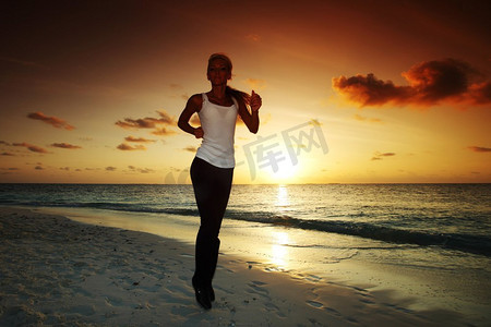 女人沿着日出或日落后的海岸线奔跑。一名女子在日落时跑步